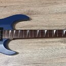 Modrá elektrická kytara s matným povrchem a tmavým hnedým hmatníkem. Na hlavě je bílý nápis framus. Kytara má dva humbuckery, tremolo mechanismus a d…