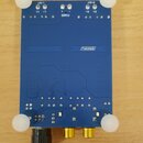 Modrá obdélníková elektronická deska s bílým nápisem SANWU. V horní části jsou nápisy L-OUT, L+, L-, POWER, R+, R- a R-OUT. V dolní části jsou dva zl…