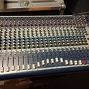 Modrý mixážní pult s kovovým panelem a множеstvem potenciometrů, přepínačů a posuvníků. V pravé dolní části je viditelné logo Soundcraft a označení m…