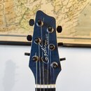 Detail hlavy modré kytary s nápisem Godin a menším textem model LGXT. Na hlavě jsou vidět šest ladicích kolíčků a struny vedené přes bílou matici. Po…
