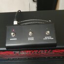 Černý obdélníkový spínací pedalboard s třemi stoupacími spínači. Nad spínači jsou umístěny kontrolní LED diody a pod nimi bílé nápisy CHANNEL, REVERB…