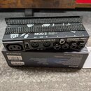 Černý kovový box s nápisy MOD 2 a ROCKBOARD MOD 2 All-in-One TRS/MIDI/USB Patchbay. Na zadní straně jsou čtyři TRS konektory označené písmeny A, B, C…