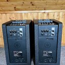 Dva černé aktivní reproduktory s texturovaným povrchem. Na zadní stranách jsou viditelné konektory pro vstup a výstup, ovládací prvky a logo Yamaha.…