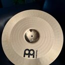 Kruhový mosazný činel s kovaným povrchem v okrajové části. Na spodní části je černý nápis MEINL a vedle něj velké stylistické logo v podobě písmen M…
