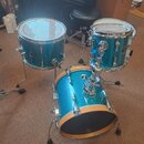 Modrázlatý bubnový set se třemi kotli v metalickém provedení. Na přednímstěně basového bubnu je vidět nápis Muziker. Povrch nástrojů vykazuje běžné z…