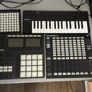 Sada černých MIDI kontrolérů a samplerů značky Native Instruments. Na fotce jsou vidět zařízení s nápisy KOMPLETE, MASCHINE a MASCHINE JAM. Všechny n…