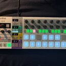 Bílá sekvenční kontrolér s názvem ARTURIA a podtitulem YOUR EXPERIENCE YOUR SOUND. Zařízení obsahuje několik řad otočných knoflíků, digitální displej…