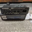 Černý patchbay s nápisem ROCKBOARD by WARWICK MOD 2 All-in-One TRS/MIDI/USB Patchbay. Zařízení obsahuje čtyři jack konektory označené písmeny A, B, C…