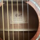 Fotografie zachycuje pohled do ozvučnice akustické kytary. Uvnitř je vidět štítek s nápisy „Cort GUITARS“, „MODEL: AP550M OP“, „SERIAL NO: IA21076037…