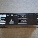 Zadní strana černého elektronického zařízení s několika konektory. Jsou zde nápisy CHANNEL 1, OUTPUT a INPUT u jednotlivých vstupů a výstupů. Na štít…