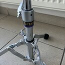 Detail chromovaného stojanu s kovovou základnou a stříbrným utahovacím knoflíkem. Na stojanu je černé štítku s žlutým logem a nápisem YAMA, pod který…