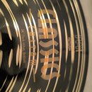 Detail zlatavého činchimu s koncentrickými drážkami. Na povrchu je žlutý nápis CLASSIC CUSTOM a bílý text 14" Dark-Hihat, Bottom. Vedle je viditelné…