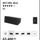 Snímek zobrazuje dva černé lineární reproduktory s texturovaným povrchem. Na přední straně je viditelné bílé logo RCF. V horní části obrázku je text…