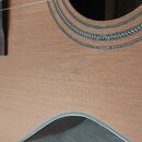 Detailní záběr na přední desku akustické kytary s viditelnou sletovkou a hřístem. Kolem otvoru kytary je dekorativní rozetový ornament s pleteným vzo…