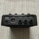 Zadní strana černého elektronického zařízení s několika konektory. Jsou zde nápisy power (s označením 12V DC/380mA), MIDI, ext.sw, input a output. Po…