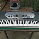 Šedý digitální klavír s bílými a černými klávesami. Na levé straně ovládacího panelu je nápis CASIO a na pravé straně TOUCH RESPONSE. V pravém dolním…