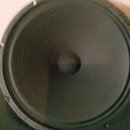 Fotografie zobrazuje černý kruhový reproduktor. Membrána má výraznou koncentrickou strukturu s centrally umístěným kalotou. Na viditelných částech ne…