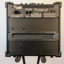 Zadní strana černého komba značky Roland. V horní části je štítek s nápisy: Roland, AC 230 V~50Hz 24 W, MODEL: KC-10, SERIAL NO. 249565, MADE IN CHIN…
