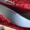 Detailní záběr na hranu černého nástroje s matným povrchem. Na hraně je viditelný malý odřap, který odhaluje světlejší barvu materiálu pod lakem. V h…