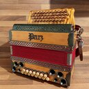 Dřevěný harmonika s červeným měchem a kovovými ozdobnými prvky v rozích. Na přední dřevěné části je černý nápis „Parz“. Nástroj má řadu malých dřevěn…