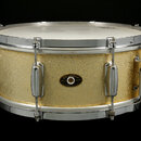 Zlatý buben s kovovými obručemi a ladidly. Uprostřed korpusu je oválný štítek s nápisy „Slingerland“, „QUALITY DRUMS“ a „CHICAGO, ILL. U.S.A.“. Povrc…