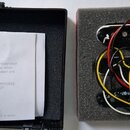 Fotografie zobrazuje sadu tří elektrických snímačů s černými plastovými kryty a bílými rámečky, položených na šedé pěnové vložce. Snímače mají připoj…