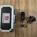 Černý kufr s hliníkovými hranami a nápisem SE ELECTRONICS a logem SE. Vedle kufru je černý mikrofon s nápisem sE a modelem sE4100, kabel a černý držá…