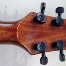 Zadní strana hlavy akustické kytary z hnědého lakovaného dřeva. Jsou zde vidět šest černých ladicích mechanismů s hranatými knoflíky. Na dřevě nejsou…