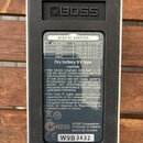 Zadní strana stříbrného efektpedálu značky BOSS. Na spodní části je umístěn informační štítek s tabulkou pro BOSS AC ADAPTOR a textem o kompatibilitě…
