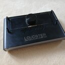 Černý obdélníkový přenosný zesilovač z kovového materiálu. Na horní straně je nápis HOTONE, PORTABLE FLOOR POWER AMP a NANO LEGATO PLUG. Zařízení má…