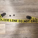 Žlutý popruh s černým nápisem POLICE LINE DO NOT CROSS. Má černé koncové leather strapky a dvě samostatné černé podložky. Povrch popruhu je hladký, b…
