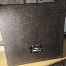 Zadní strana černého kytarového komba s povrchem z texturovaného vinylu. V dolní části je umístěn ovládací panel s dvěma vstupy a jedním výstupem, u…