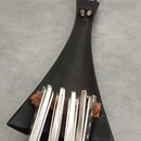 Černý kalimba v trojúhelníkovém tvaru s kovovými plátky. Nástroj je vyroben z černého materiálu a má v horní části připevněné černé očko. Na povrchu…