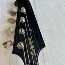 Černá hlava basové kytary s nápisem Epiphone v bílém skleptovém písmu. Jsou na ní vidět čtyři chromované ladičky s kovovými knoflíky. Povrch je hladk…