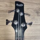 Černá hlava basové kytary s chromovanými kolíky. Na čele jsou bílá loga GIO, Ibanez a nápis SOUNDGEAR. Na horní části hmatníku je vidět nápis Ibanez.…