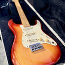 Elektrická kytara s trupem v červeno-žlutém sunburst provedení a bílým pickguardem. Nástroj má javorový hmatník a tři snímače typu single-coil. Na hl…