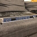 Stříbrné rackové zařízení s černým horním panelem, na kterém je schéma zapojení. Na předním panelu jsou nápisy INPUT LEVEL, LIMITER, INPUT STATE, MET…