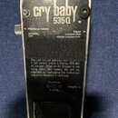 Stříbrný efekt pedál s nápisem cry baby 535Q. Na povrchu jsou texty WAH Range Selector (CLOCKWISE: Low), Volume (CLOCKWISE: High, COUNTER CLOCKWISE:…