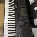 Černý digitální klavír s bílými a černými klávesami. Na ovládacím panelu je viditelné logo YAMAHA a označení modelu PSR-SX700. Nástroj obsahuje displ…