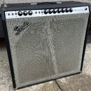 Kytarový kombozesilovač s černým krytím z vinylu a stříbrnou tkanou přední síťovkou. Na horním ovládacím panelu jsou nápisy NORMAL, VIBRATO a SUPER R…