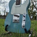 Modře lakovaná elektrická kytara typu Telecaster s bílým pickguardem a hnedým hmatníkem. Nástroj má dva snímače, jeden z nich je umístěn v chromované…