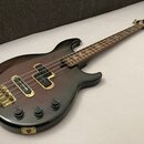 Elektrická basová kytara s tmavým, přechodovým lakem od červené po černou. Na hmatníku jsou vidět čtyři vložky s nápisem "YAMAHA". Nástroj má zlatý h…