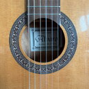 Detail kytary s vyvedeným otvorem, který je obklopen ornamentální rozetou. Uvnitř otvoru je štítek s nápisy GUITARRAS, Alvaro a Modelo NO.27 3/4 oraz…