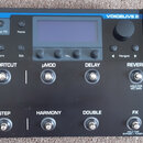 Černý procesor efektů s nápisy TC-HELICON a VOICELIVE 2. Zařízení má displej, ovládací knoflíky a dvě řady stomačkových spínačů s popisky PRESET, SHO…