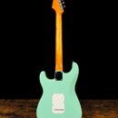 Zadní pohled na elektrickou kytaru s mint-green tělem a hnědým javorovým krkem. Na hlavě je viditelné logo Fender. Zadní kryt elektroniky je bílý a p…