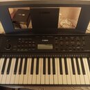 Černý digitální klavír značky YAMAHA s bílými a černými klávesami. Na ovládacím panelu je centrálně umístěn nápis YAMAHA a digitální displej. Nástroj…
