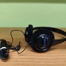 Černá sluchátka s hlavovým obloukem a polstrováním z černé pěny. Na vnější straně pravého sluchátka je modrý nápis ROCKMAN. Sluchátka mají připojený…