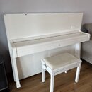 Bílé digitální piano s doprovodnou bílou stoličkou s polstrovaným sedákem. Nástroj má hladký, lesklý povrch bez viditelných značek, log nebo modelový…