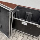 Otevřený transportní kufr s hliníkovým profilem a černým povrchem. Vnitřek je vyložen černou pěnou s několika výřezy pro vybavení. Na vnější straně j…