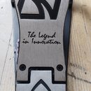 Detail kovového pedálu s nápisem TAMA a sloganem The Legend in Innovation. Povrch je stříbrný s broušeným efektem a černými grafickými prvky. Na spod…